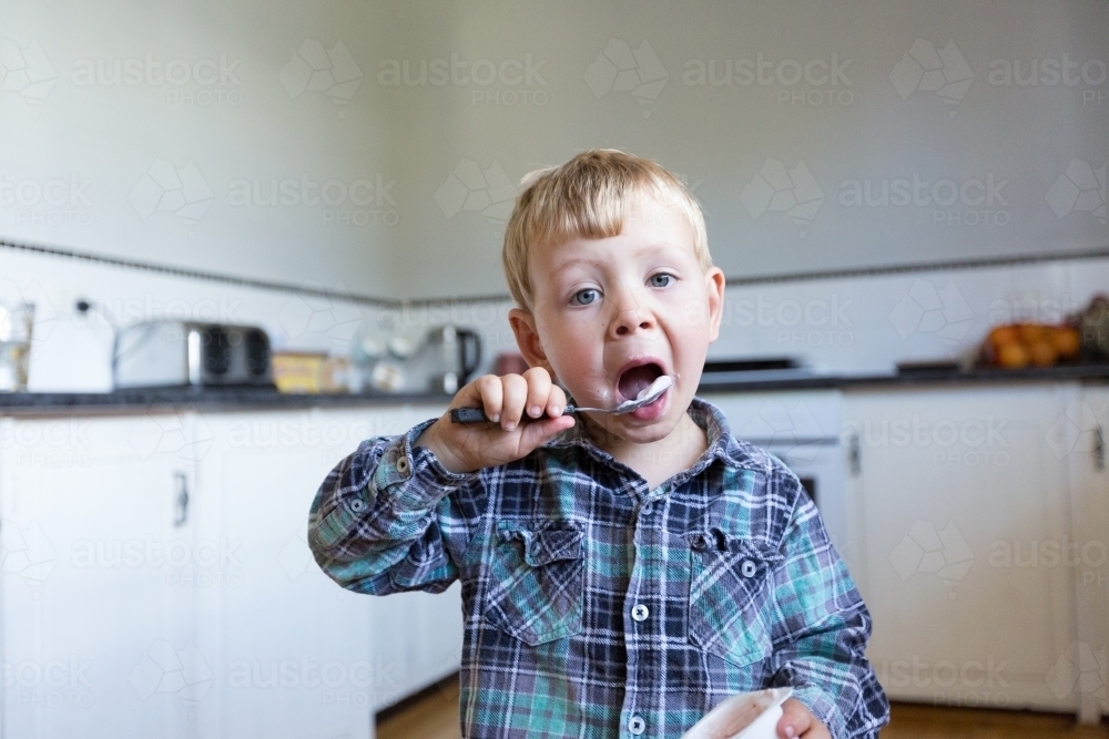 Child eating yoghurt with a spoon - Australian Stock Image