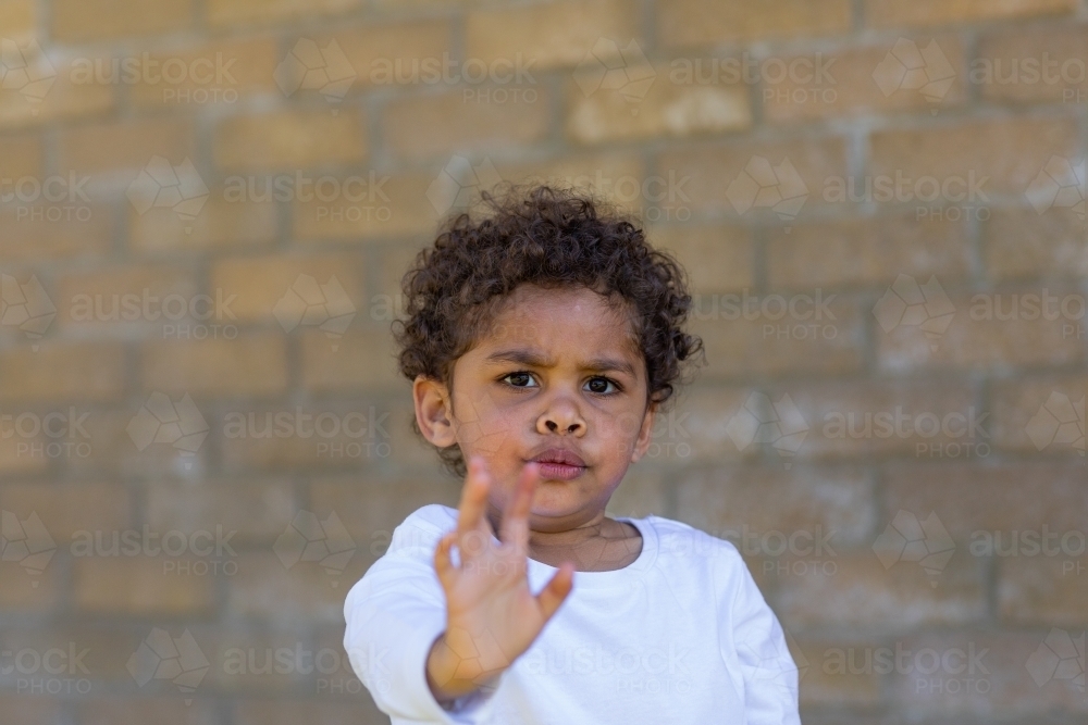 child frowning with hand up signalling stop - Australian Stock Image