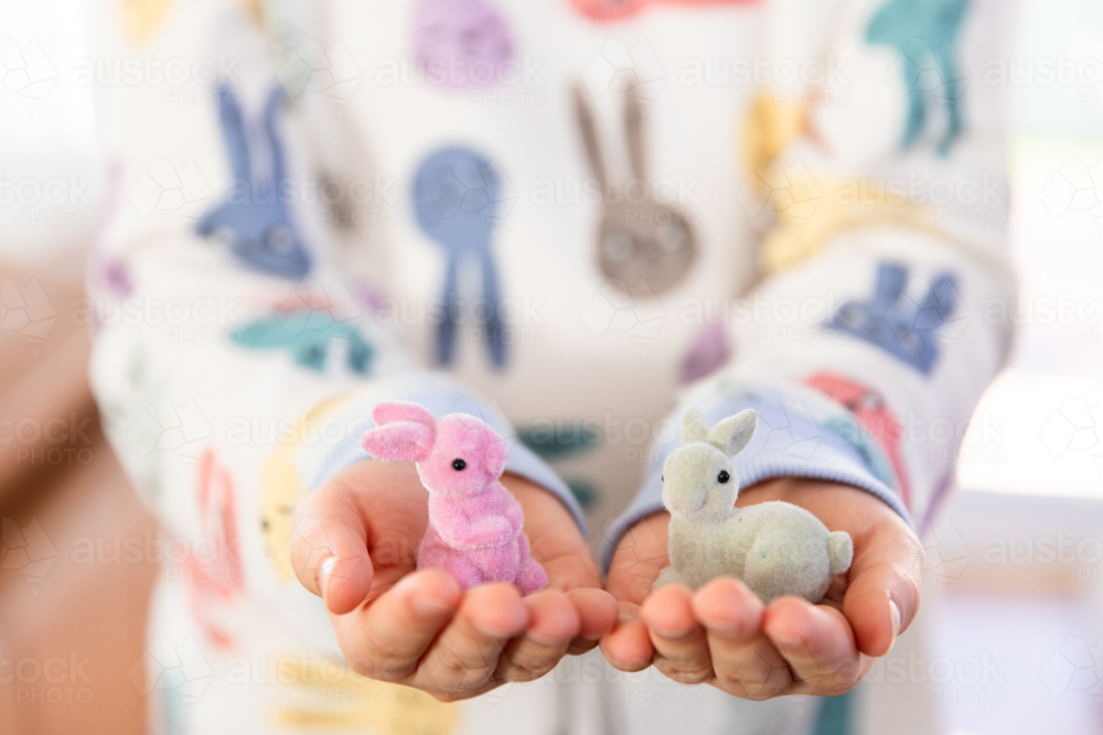 child holding a pair of easter bunny figurines in their hands - Australian Stock Image