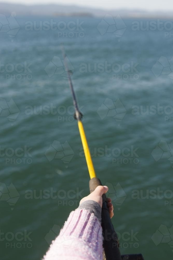 Image of Child holding a yellow fishing rod over water - Austockphoto