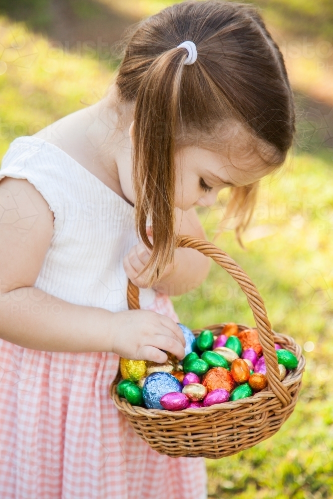 Child hunting for Easter eggs in garden on sunlit morning - Australian Stock Image