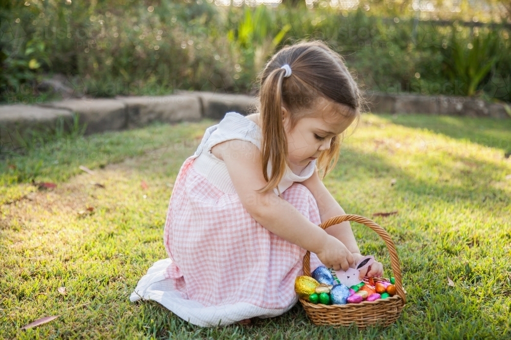 Child in garden putting Easter bunny in egg basket - Australian Stock Image