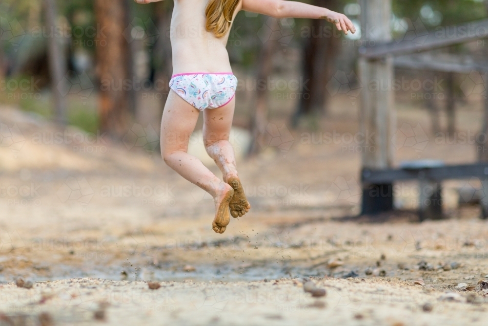 Child in her undies jumping in a muddy puddle - Australian Stock Image
