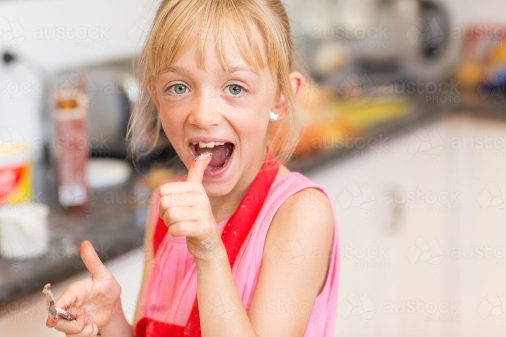 Child in the kitchen putting thumb in her mouth - Australian Stock Image