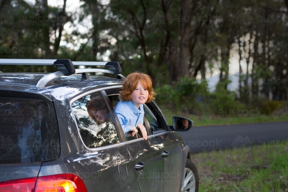 Child leaning out of car window on the side of the road - Australian Stock Image