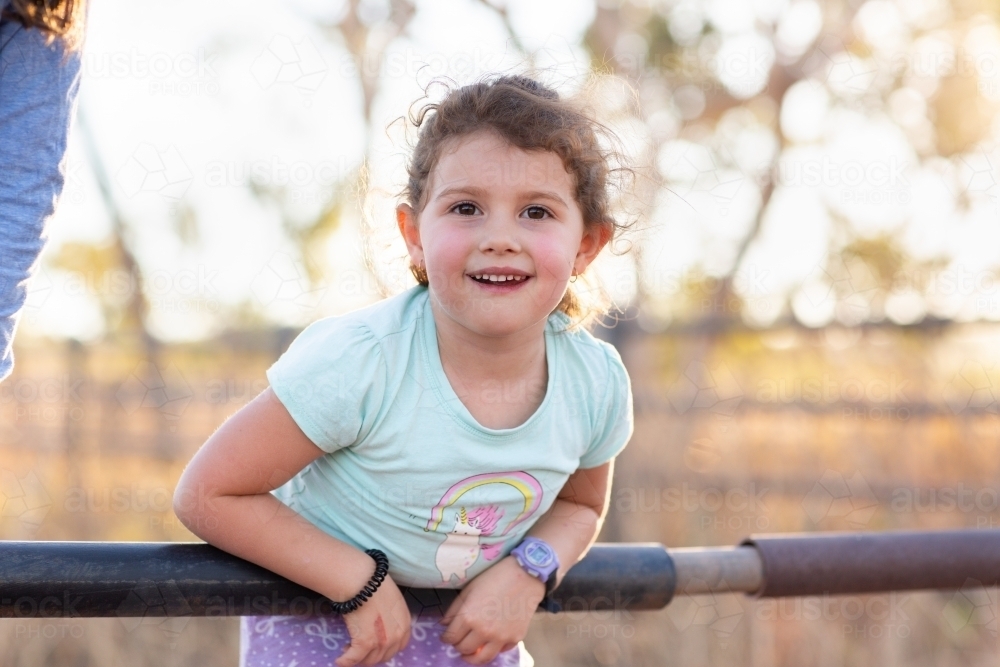Child leaning over rail on yards - Australian Stock Image