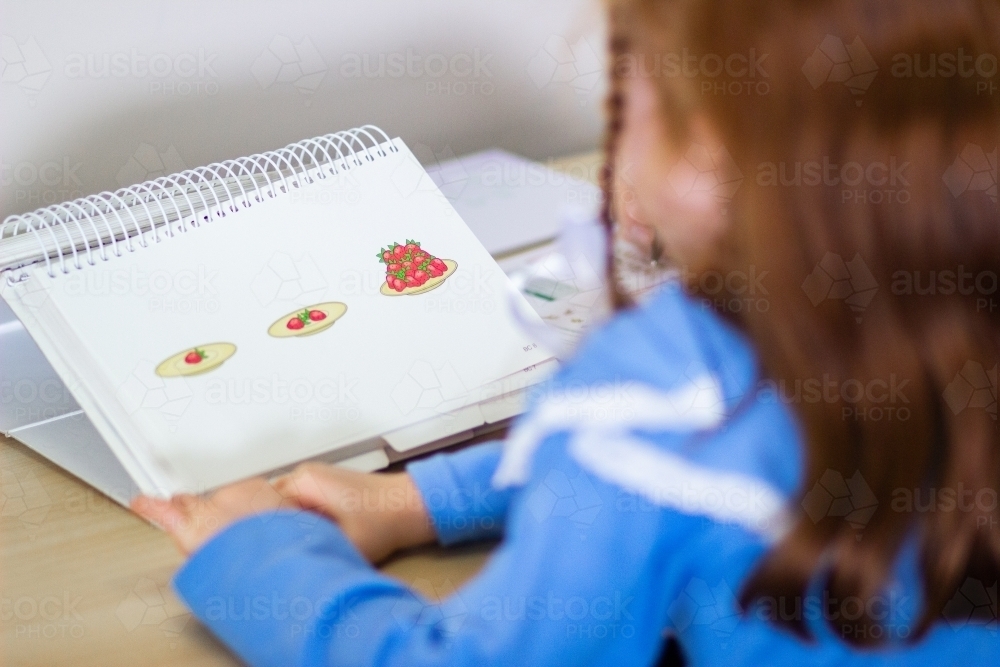 Child looking at speech therapists picture book - Australian Stock Image