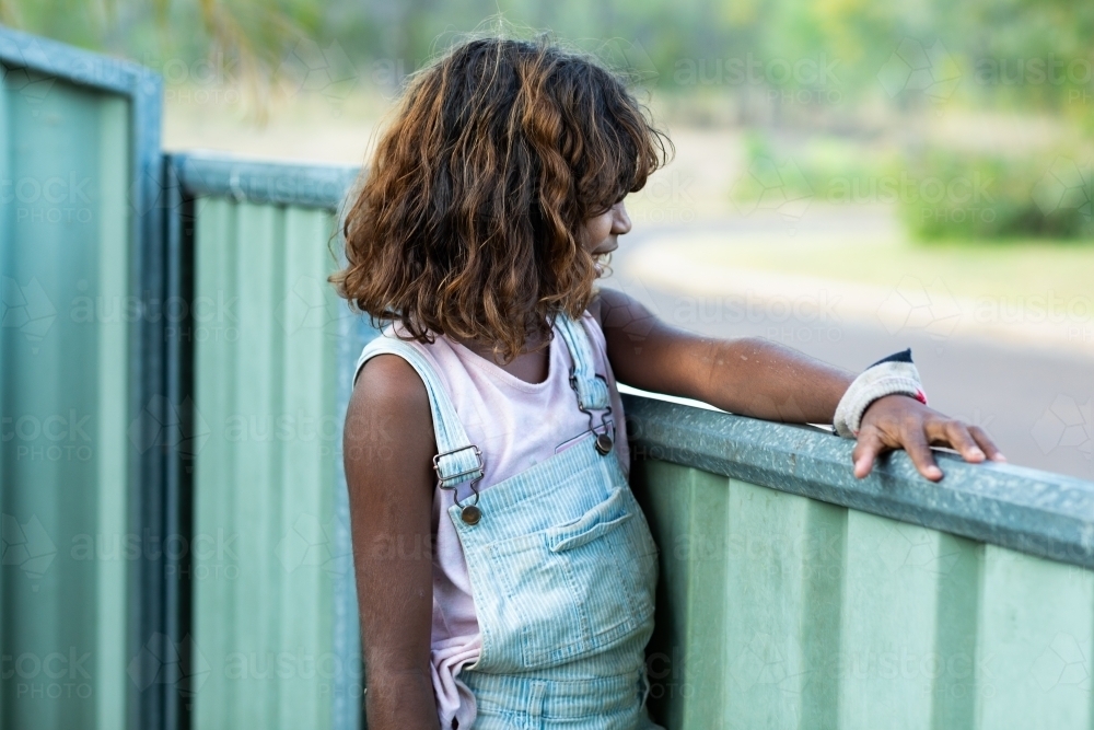 child looking out over metal fence - Australian Stock Image