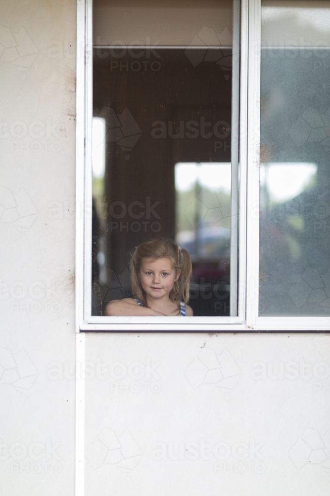 Child looking out window through flyscreen - Australian Stock Image