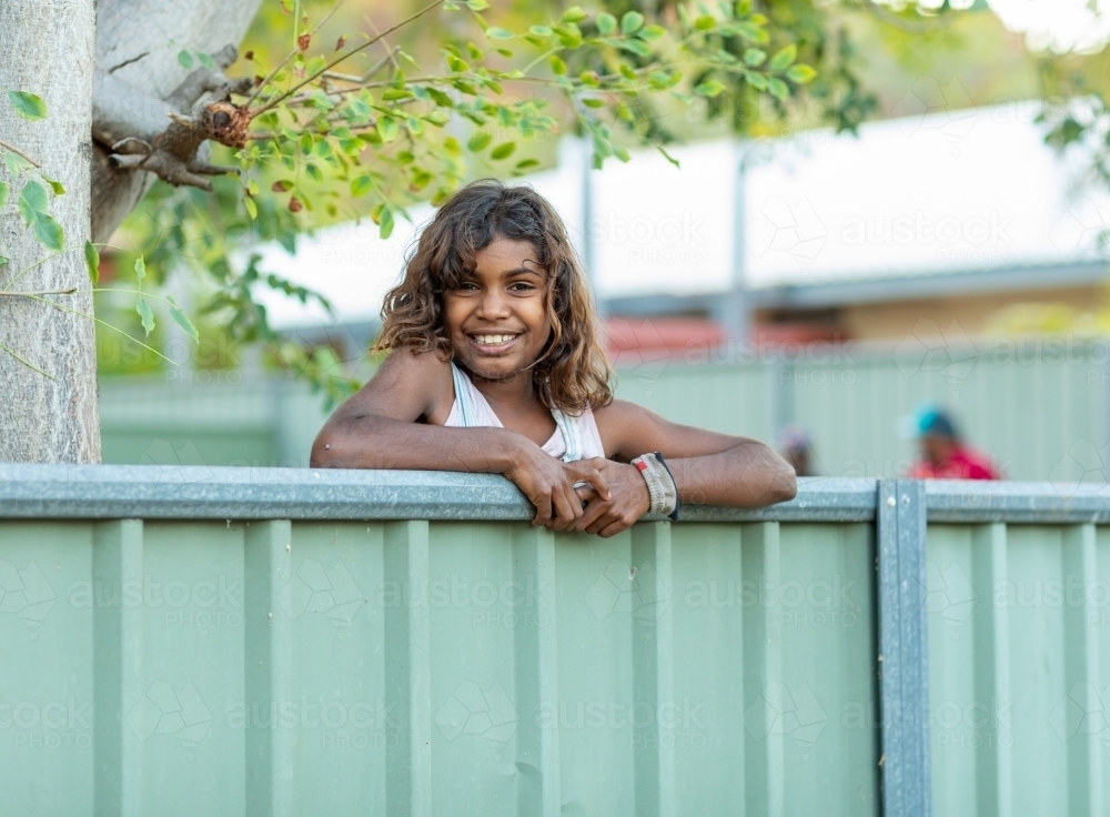 child looking over fence in house yard - Australian Stock Image