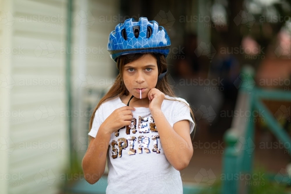 Child looking sullen sucking on lollipop - Australian Stock Image