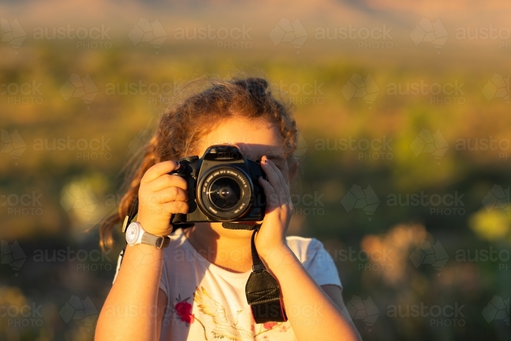 Image of child looking through DSLR camera taking photo of viewer