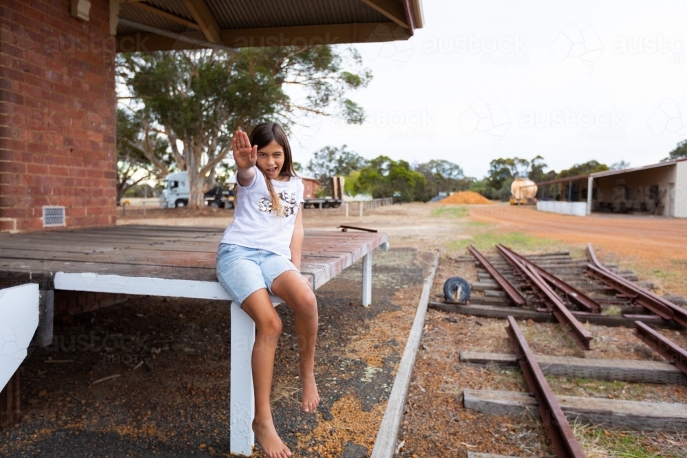 child near disused railway line holding out hand in stop signal - Australian Stock Image