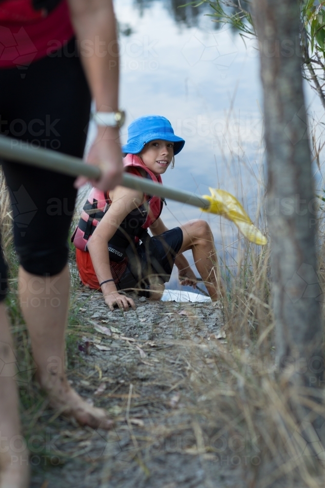 Child on riverbank with kayak paddle - Australian Stock Image