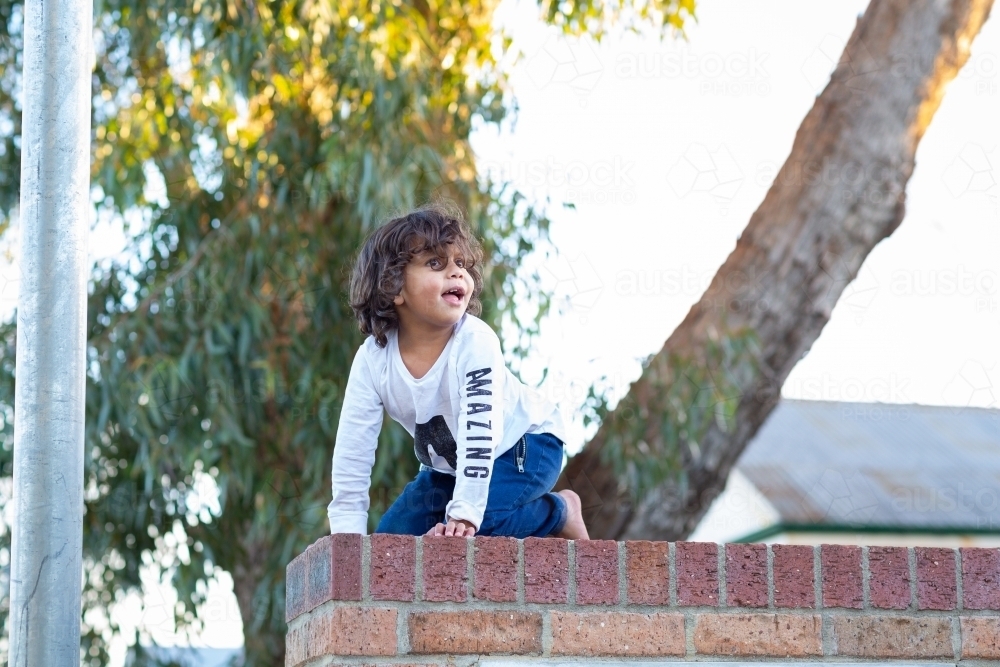 Child perched on a brick wall - Australian Stock Image