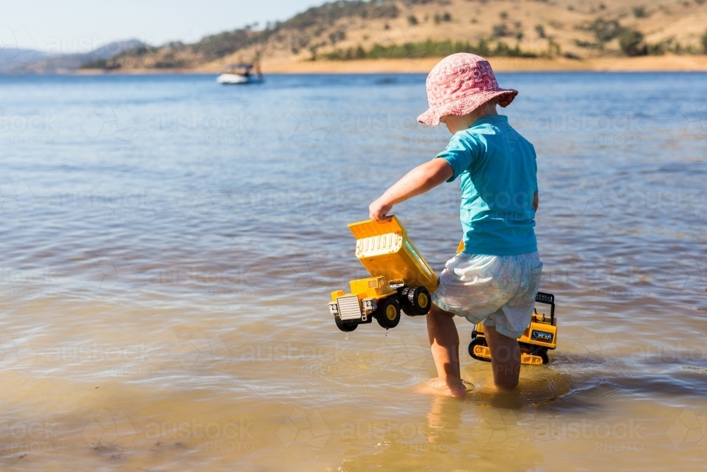 Child playing in the water with toys at Wyangala dam - Australian Stock Image