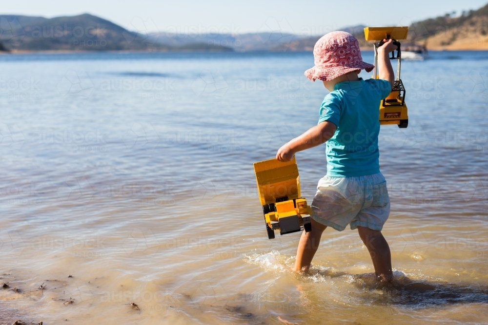 Child playing in the water with toys at Wyangala dam - Australian Stock Image