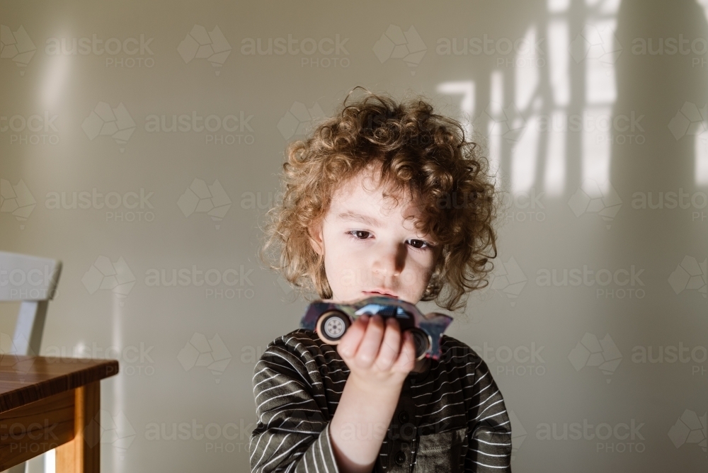 Child playing with a handmade model kit wooden toy car - Australian Stock Image