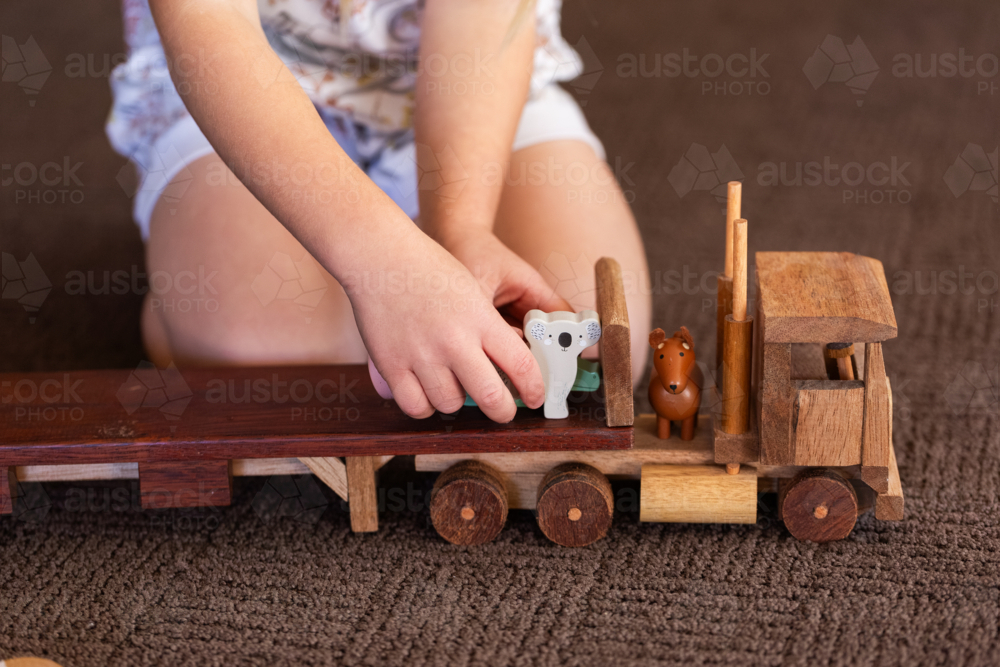 Child playing with animals on flatbed truck for imaginative play - Australian Stock Image