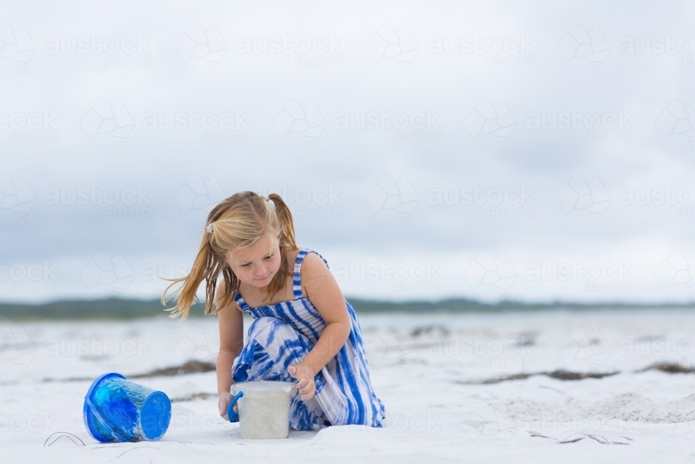Child playing with bucket on beach - Australian Stock Image