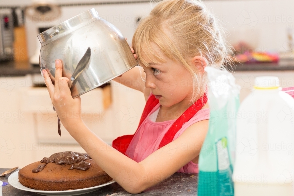 Child pouring icing onto a cake - Australian Stock Image