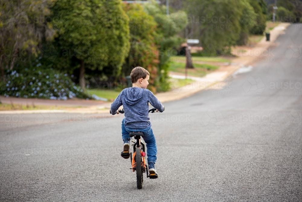 Child riding bike on road with no helmet - Australian Stock Image