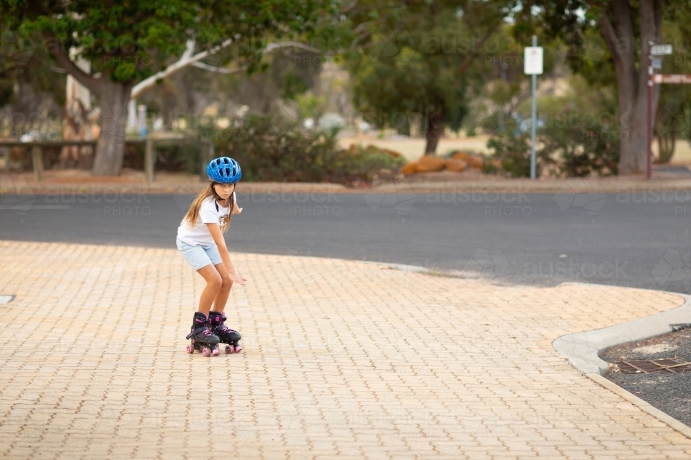 child rollerskating on paved footpath in country town - Australian Stock Image