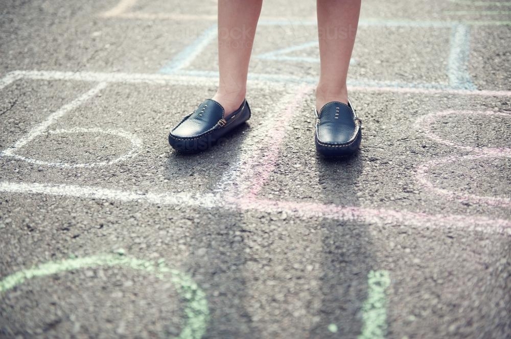 Child's feet standing on hopscotch squares - Australian Stock Image