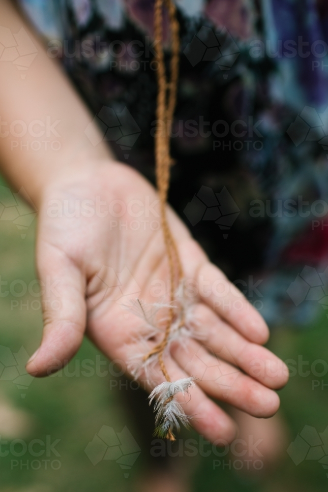 Child's hand holding string with feathers attached - Australian Stock Image