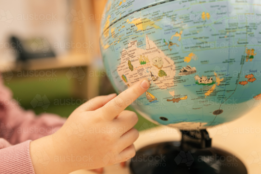 Child's hand pointing to Australia on world globe at kindergarten - Australian Stock Image