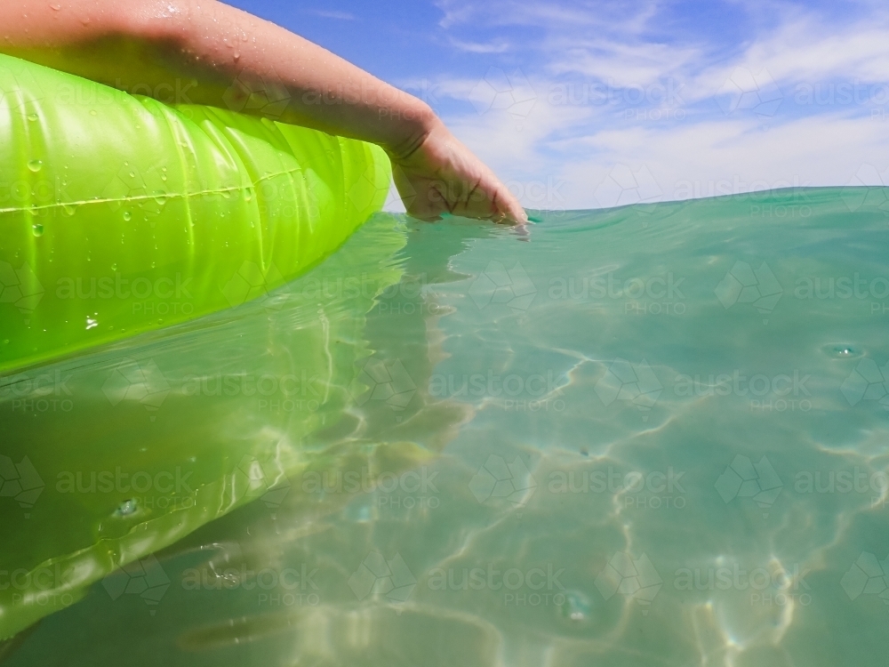 Child's hand resting in calm ocean water - Australian Stock Image