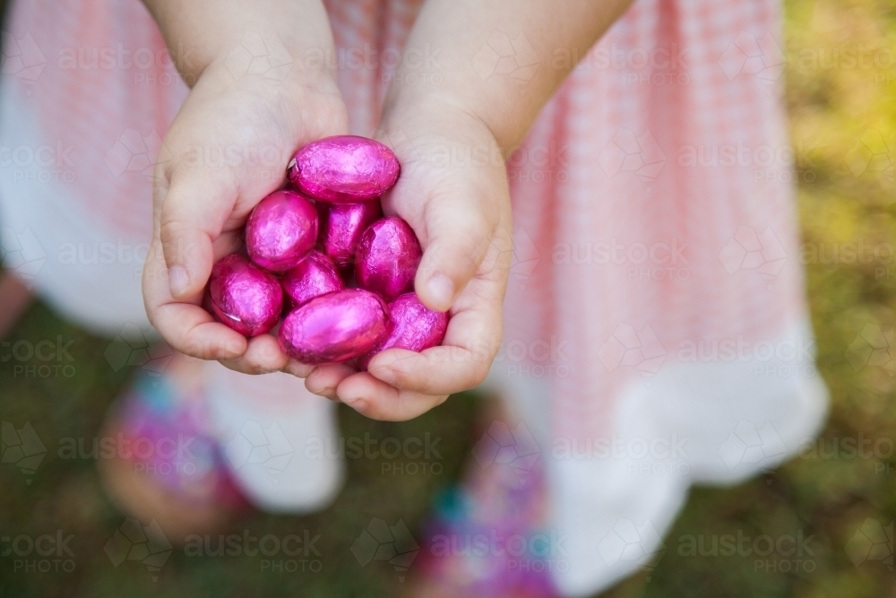 Child's hands hold out pink easter eggs - Australian Stock Image