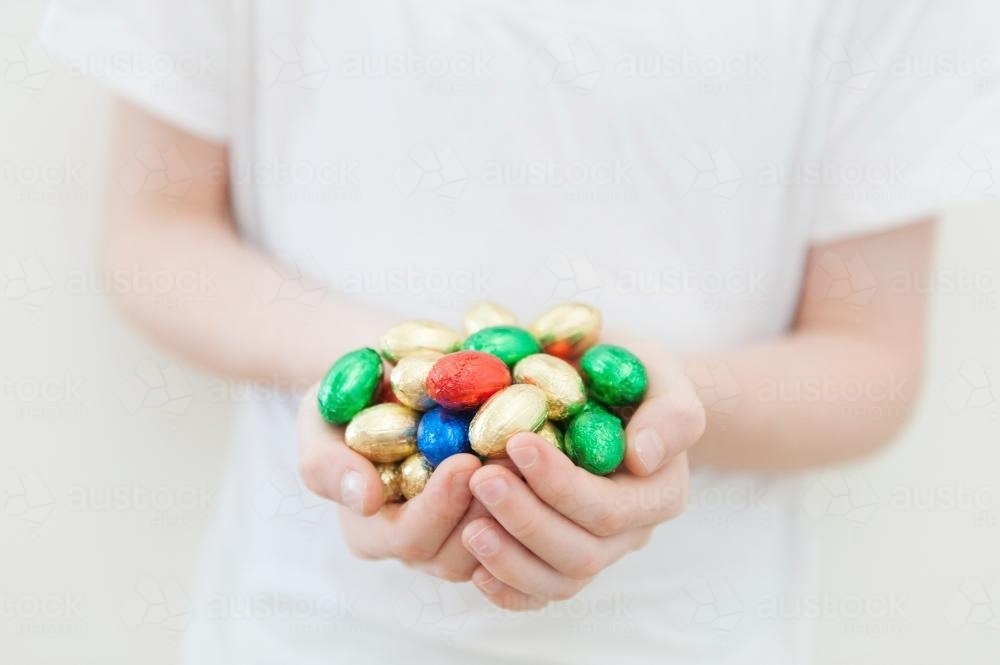 Child's hands holding coloured mini easter eggs - Australian Stock Image