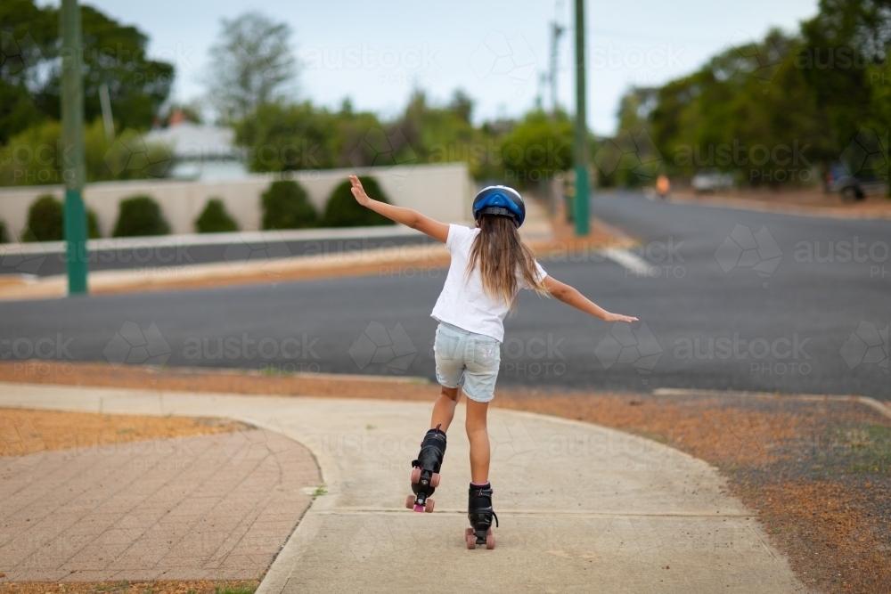 Child seen from behind rollerskating on footpath - Australian Stock Image