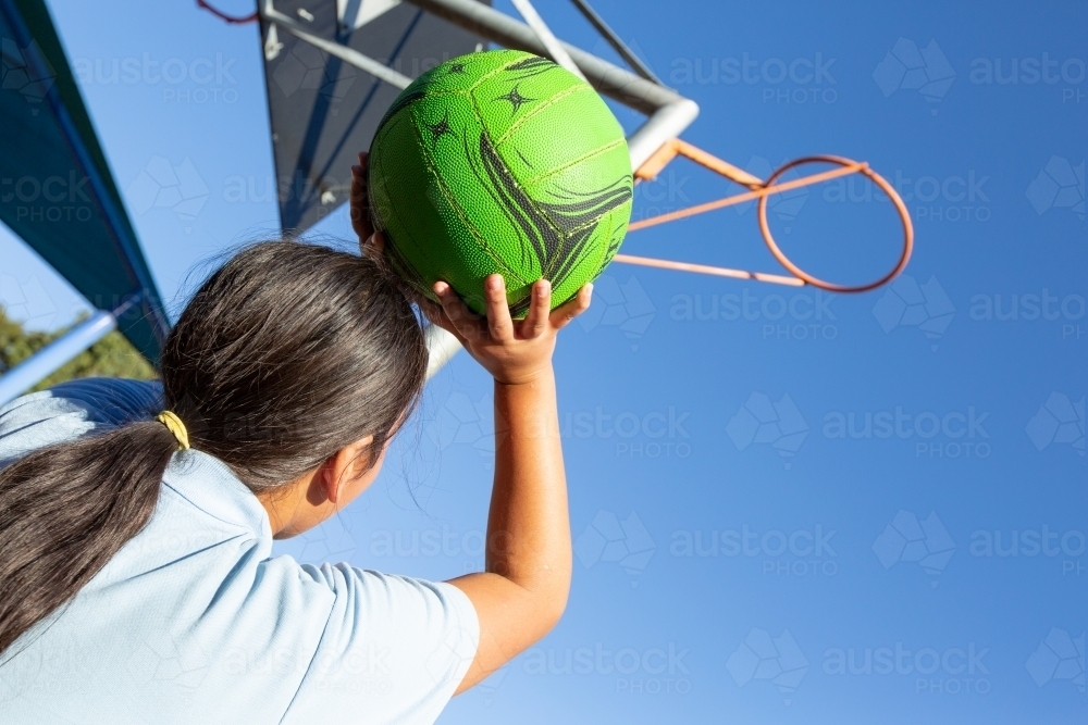 Child shooting netball goal - Australian Stock Image