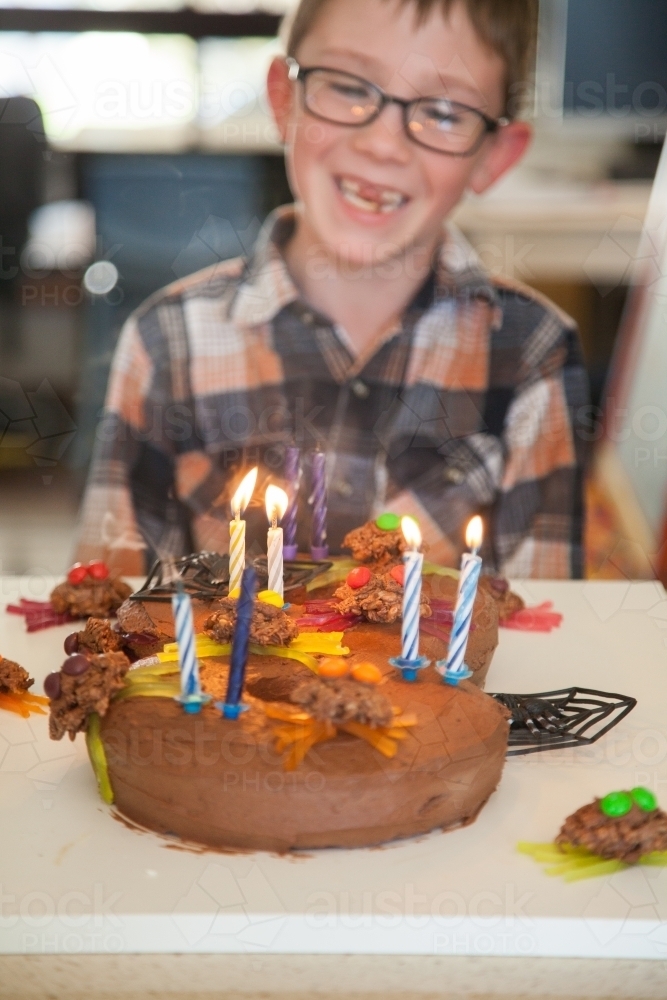 Child smiling behind number eight spider birthday cake - Australian Stock Image