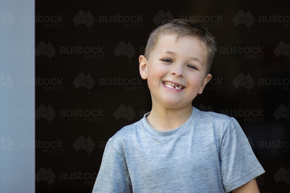 Child standing in doorway with a cheeky grin - Australian Stock Image