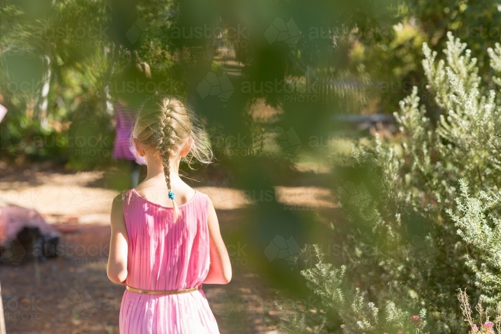 Child walking away on path through bushes - Australian Stock Image