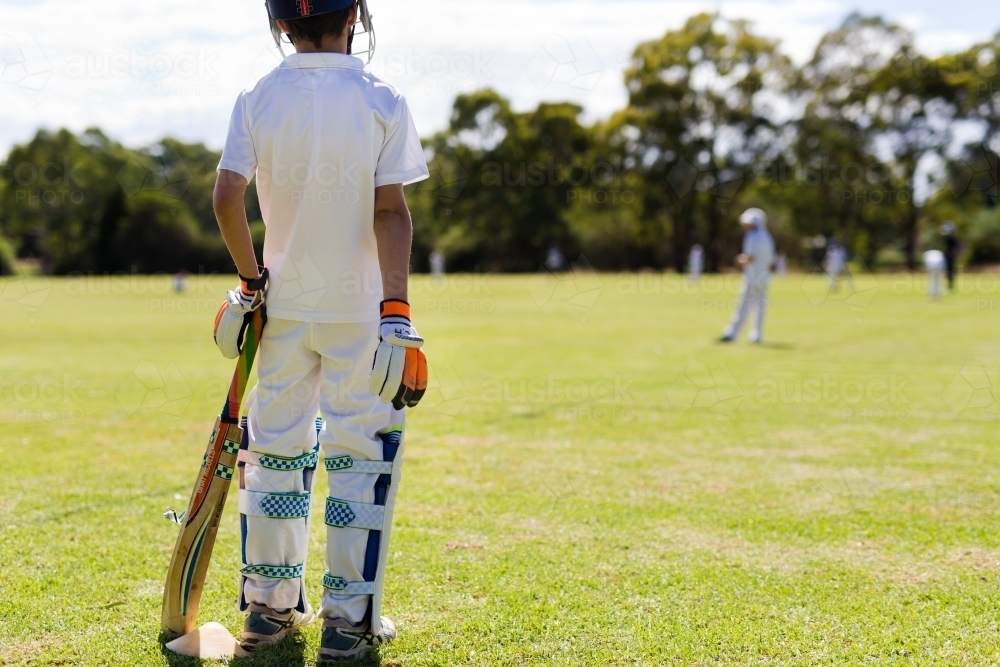 Child wearing pads waiting to bat during a game of cricket - Australian Stock Image