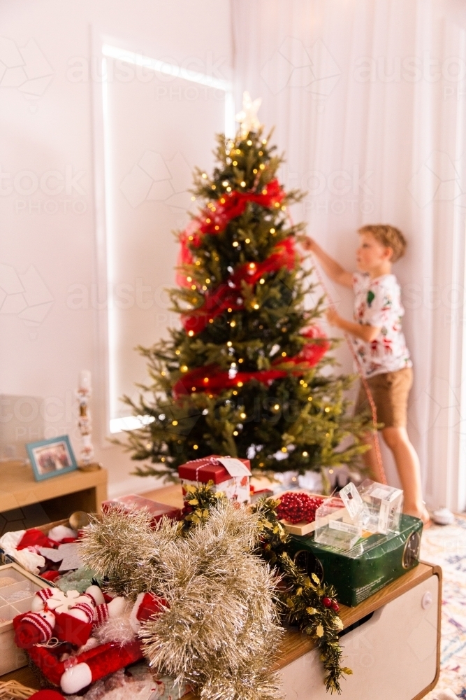 child working to decorate the Christmas Tree focus on decorations - Australian Stock Image