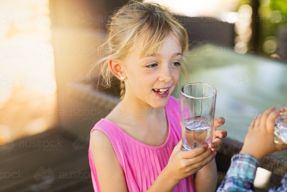 Children drinking water from a glass - Australian Stock Image