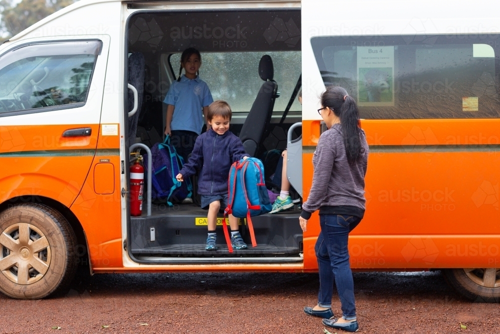 Children getting of a school bus on gravel road - Australian Stock Image