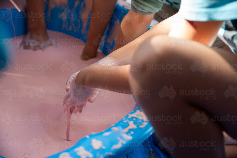 Children hands dripping with oobleck, cornstarch and water mixture, doing a science experiment - Australian Stock Image