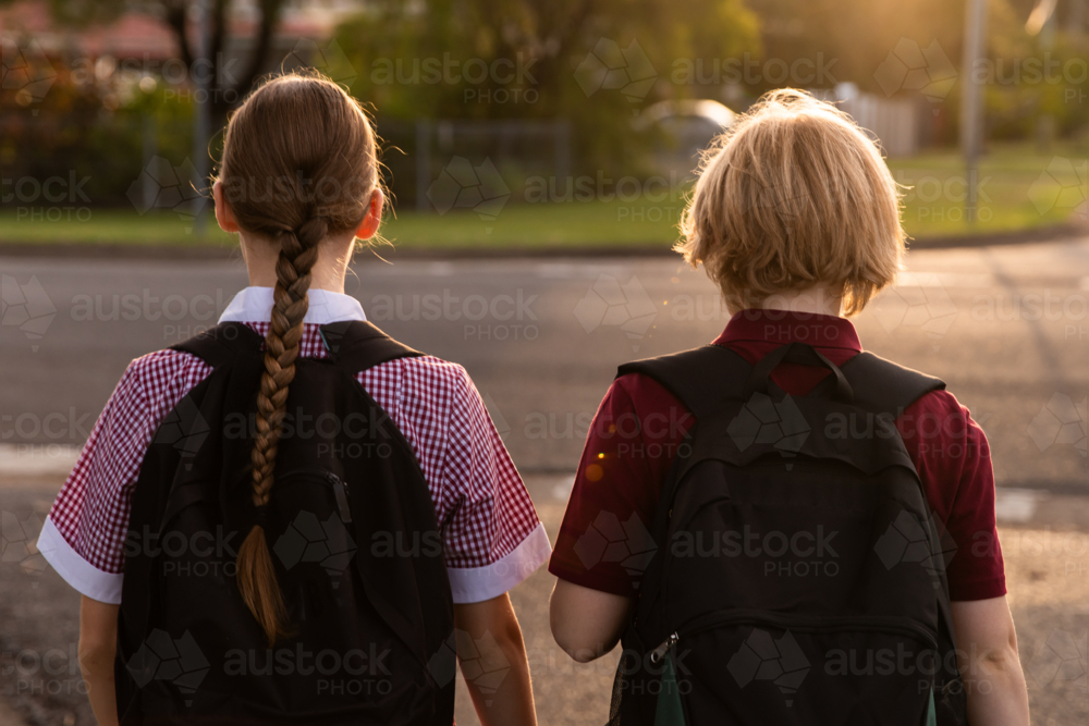 children in school uniform walking on a quiet street from the back - Australian Stock Image