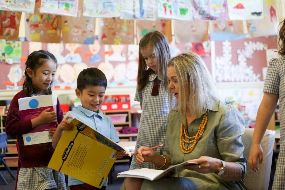 Children in the classroom, showing their work to the teacher - Australian Stock Image