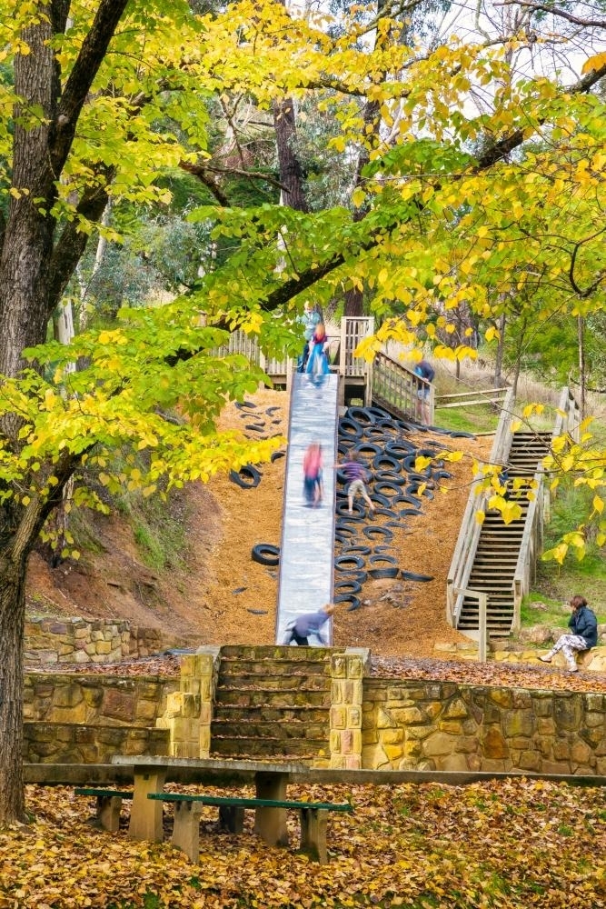 Children play on a large slide in a park in Autumn - Australian Stock Image