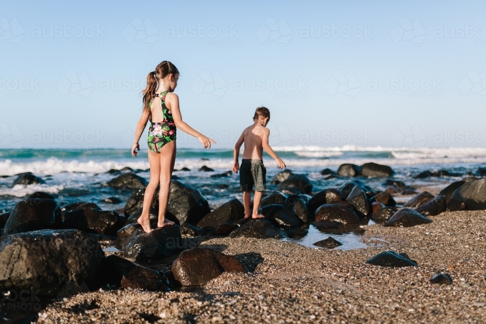 Children playing at the beach and climbing rocks - Australian Stock Image