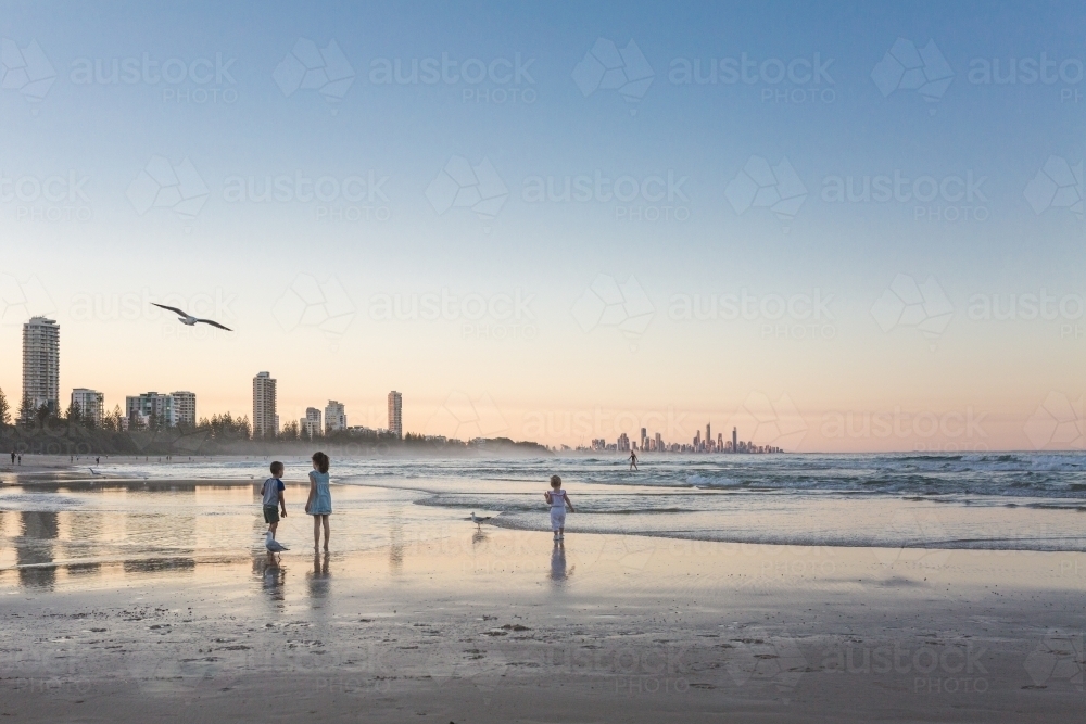 Children playing at the beach at sunset - Australian Stock Image