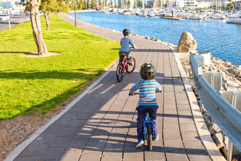 Children riding their bicycles along lake at Glenelg - Australian Stock Image