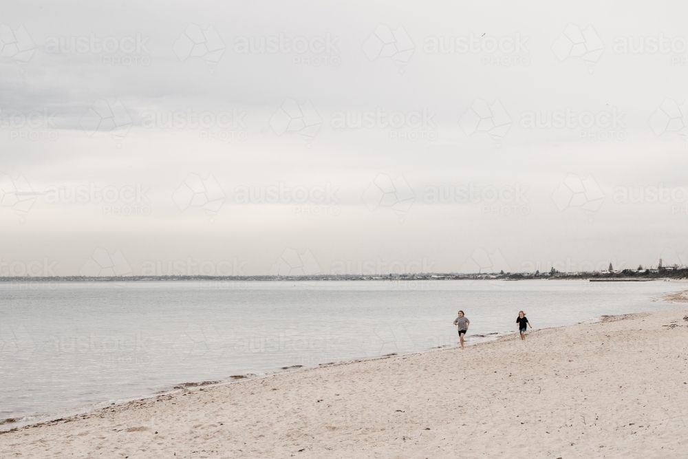 Children running along a beach in Melbourne - Australian Stock Image